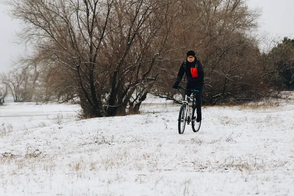Man on a bike in the winter forest front view
