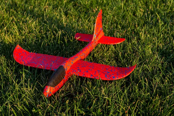 Rode speelgoed vliegtuig liggend op het gras — Stockfoto