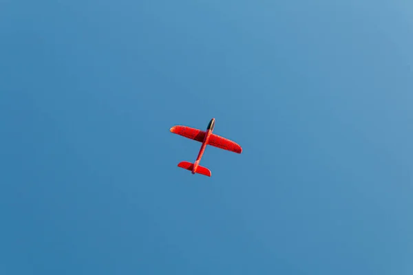 Κόκκινο αεροπλάνο παιχνίδι πετάει στον καθαρό ουρανό — Φωτογραφία Αρχείου