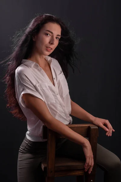 年轻的黑发女孩的肖像是坐在椅子上 — 图库照片