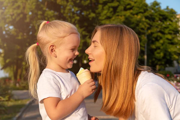Young mother and daughter eat one ice cream. — Stock Photo, Image