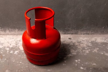 Kırmızı eski bir gaz silindiri duvara yakın katta duruyor.