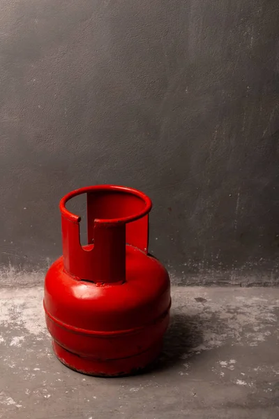 Een rode oude gascilinder staat op de vloer bij de muur. — Stockfoto