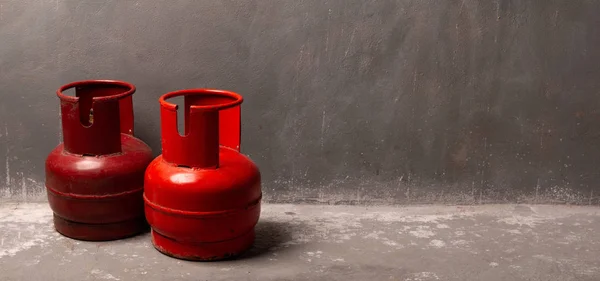 Twee oude rode gascilinders staan op de vloer in de buurt van de wal — Stockfoto