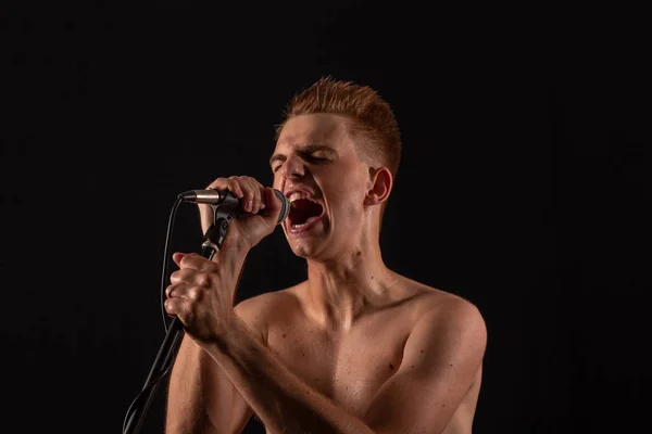 Topless guy chante punk rock dans un microphone sur un fond sombre — Photo