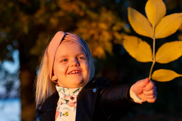 Kis lány a bőr kabát, az őszi parkban játszik. — Stock Fotó