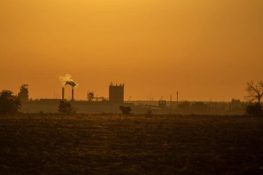 Gün batımında fabrika siluetiyle manzara
