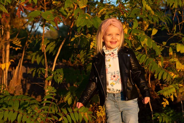 Menina em uma jaqueta de couro, jogando no parque de outono . — Fotografia de Stock