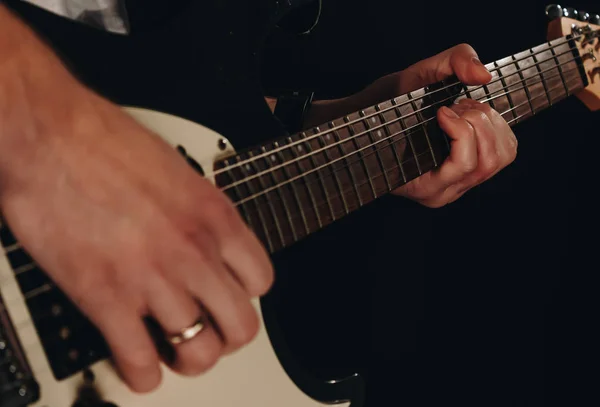 Close up shot of a man with his fingers on the guitar frets — Stock Photo, Image