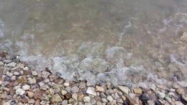 Deniz suyunda deniz taşları. Kumsalda çakıl taşları