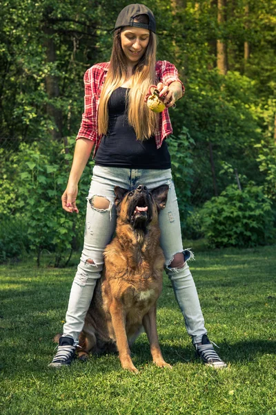 Bahçede köpek ile genç casual kadın oyun.