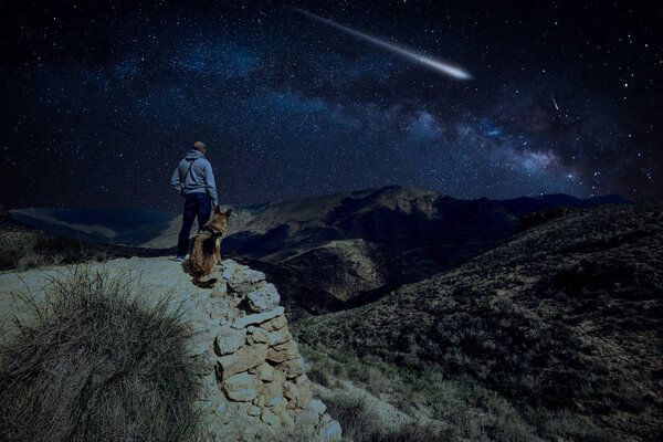Man with dog observe Perseid Meteor Shower and the Milky Way outdoor
