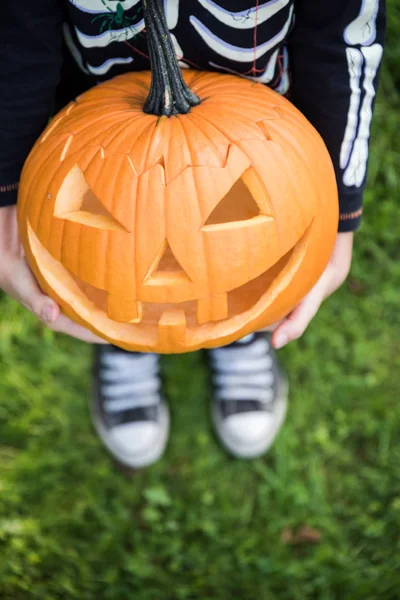 Çocuk pupmkin Cadılar Bayramı'nda tutan iskelet kostüm