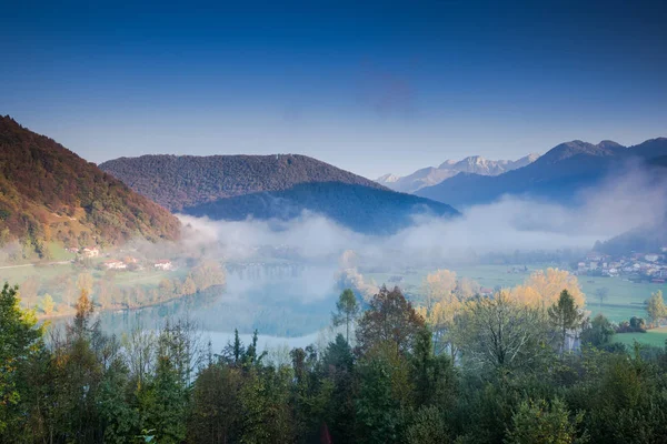 Mist over Most na Soci river with Julian Alps in Background, Slovenia.