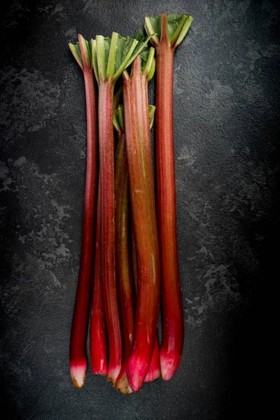 Whole fresh rhubarb steams on dark marble background — Stock Photo, Image