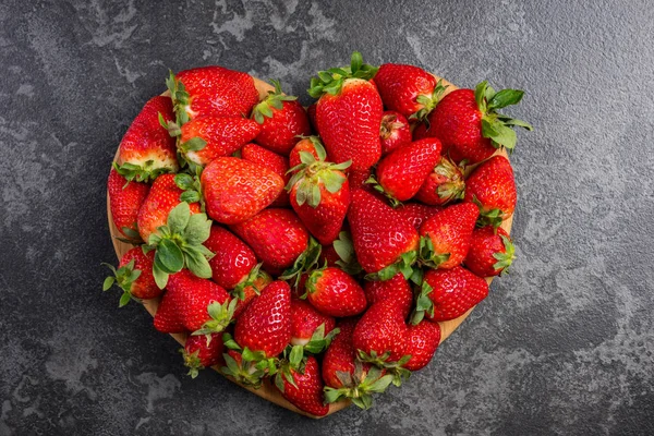 Hjärta form jordgubbar på mörk marmor, kärlek till färsk frukt — Stockfoto