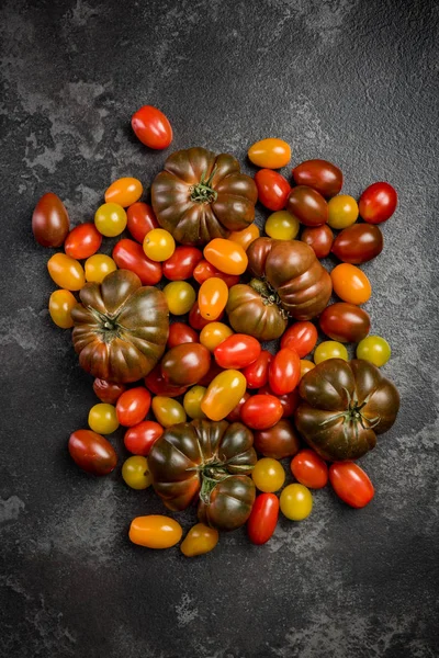 Ακατέργαστα βιολογικά πολύχρωμα ντομάτες σε φόντο σκοτεινού σχιστόλιθο — Φωτογραφία Αρχείου