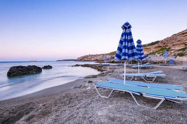 Tipici lettini prendisole sulla spiaggia di ghiaia selvaggia di Rodi, Grecia a Sunri — Foto Stock