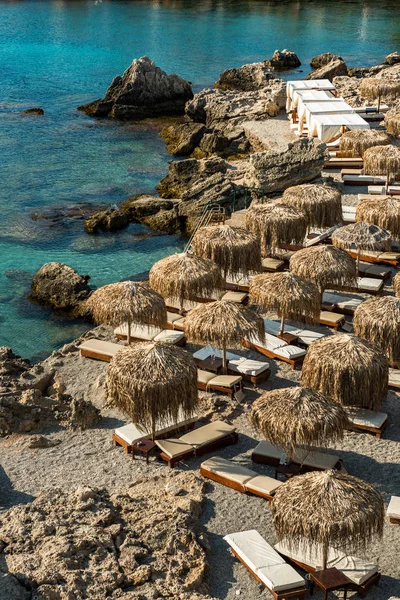 Ombrelli di bambù e lettini sulla spiaggia di ghiaia a Rodi, Grecia — Foto Stock