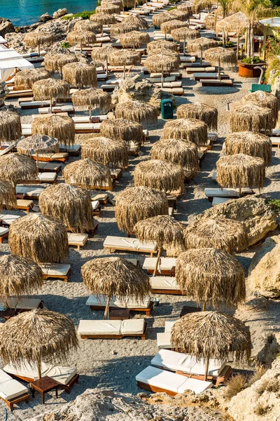 Ombrelli di bambù e lettini sulla spiaggia di ghiaia a Rodi, Grecia — Foto Stock