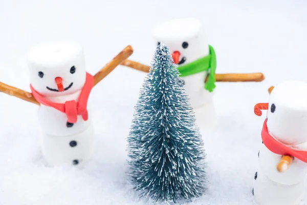 Праздничные рождественские снеговики танцуют вокруг рождественской елки в снегу — стоковое фото