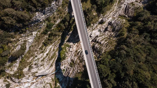 Auto rijdt over een gevaarlijke brug in Valley. Dro naar beneden vanaf de lucht — Stockfoto