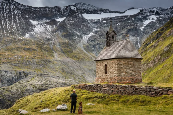 Hombre aventura con perro en la capilla solitaria de los Alpes de Alta Austria Mou — Foto de Stock