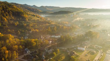 Güneşin doğuşunda, şehrin üzerinde, dağlarda, sonbahar yapraklarında yuvarlanan sis.