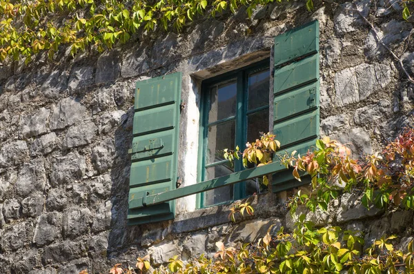 Rustic Mediterranean wooden window on the stone wall