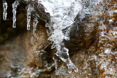 Bir taşa çözdürme buz sarkıtları Fransa dağlarda kışın duvar.