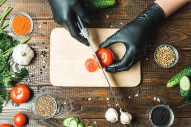 kadınların elleri kesilmiş yalan biber yanındaki bir domates, otlar, salatalık ve baharatlar