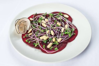 Beyaz bir plaka üzerinde otlar ile pancar salatası