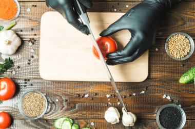 kadınların elleri kesilmiş yalan biber yanındaki bir domates, otlar, salatalık ve baharatlar