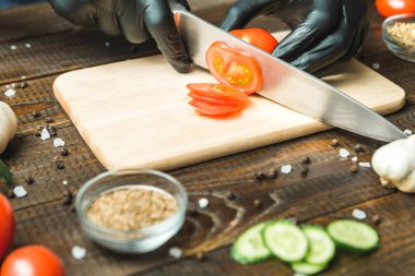 kadınların elleri kesilmiş yalan biber yanındaki bir domates, otlar, salatalık ve baharatlar