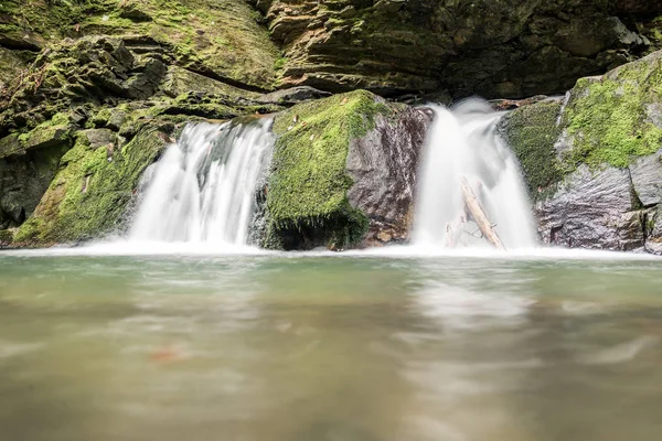 Small mountain waterfall on the rocks covered with moss in the forest