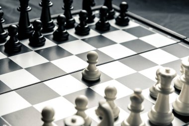 Siyah ve beyaz satranç birbirilerine bakan ile satranç masası. Beyaz piyon saldırı gider. Yatay çerçeve