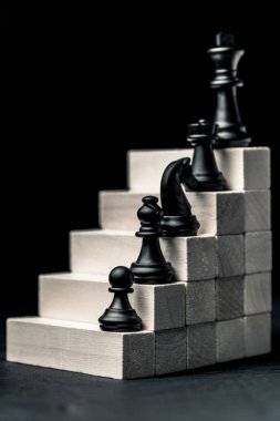 Career ladder. chess from checkers to the king stand on wooden steps. Vertical frame clipart