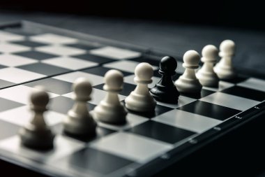 Satranç tahtası. Beyaz piyon arasında üst üste düşmanın siyah piyon duruyor. Yatay çerçeve