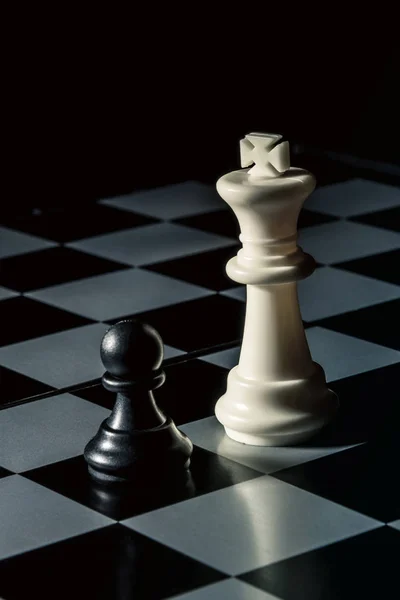 Chess board. White king threatens black opponent\'s pawn. Vertical frame