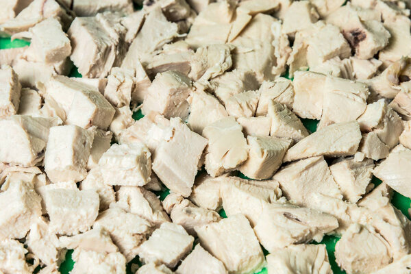 Diced boiled chicken meat on a green board. Horizontal frame