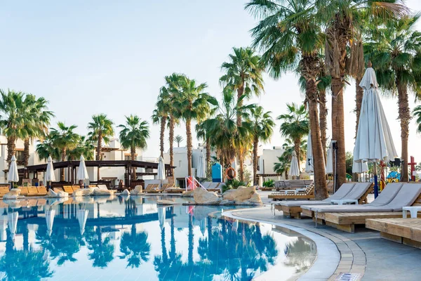 The interior of the hotel for recreation. Blue water pool, palm trees and sun beds