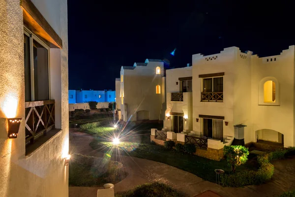 View at night on the houses of the hotel with palm trees in the background