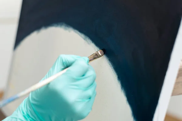 Una mano en un guante azul pinta un cuadro con un pincel. Marco horizontal —  Fotos de Stock