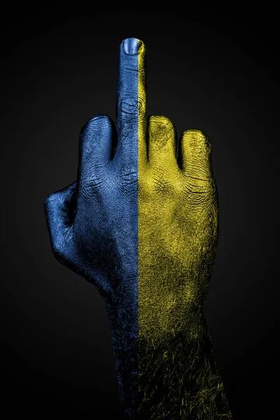 Uma mão com uma bandeira ucraniana desenhada mostra o dedo médio, um sinal de agressão, sobre um fundo escuro — Fotografia de Stock