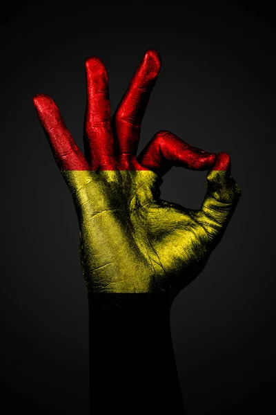 Een hand met de geschilderde vlag van België toont een OK teken op een donkere achtergrond. — Stockfoto