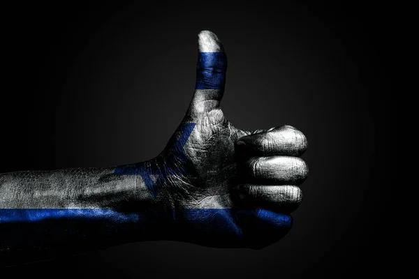 Een hand met een getekende Israël vlag toont een vinger omhoog teken, een symbool van succes, gereedheid, een taak gedaan op een donkere achtergrond. — Stockfoto