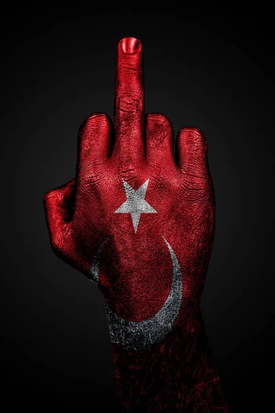 Une main avec un drapeau peint de la Turquie montre le majeur, signe d'agression, sur un fond sombre — Photo