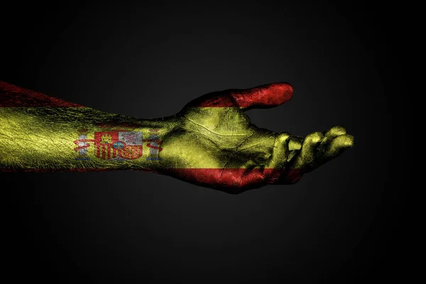 Протянутая рука с нарисованным флагом Испании, знаком помощи или просьбой, на темном фоне . — стоковое фото