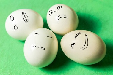yeşil tahta üzerinde farklı yüz grimaces ile dört beyaz yumurta