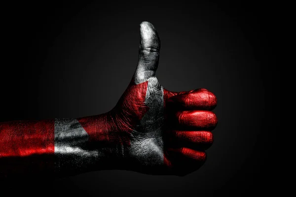 Een hand met een getekende Canada vlag toont een vinger omhoog teken, een symbool van succes, gereedheid, een taak gedaan op een donkere achtergrond. — Stockfoto